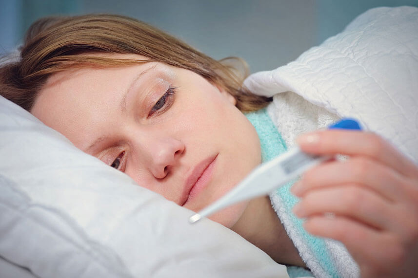 woman with cold holding thermometer